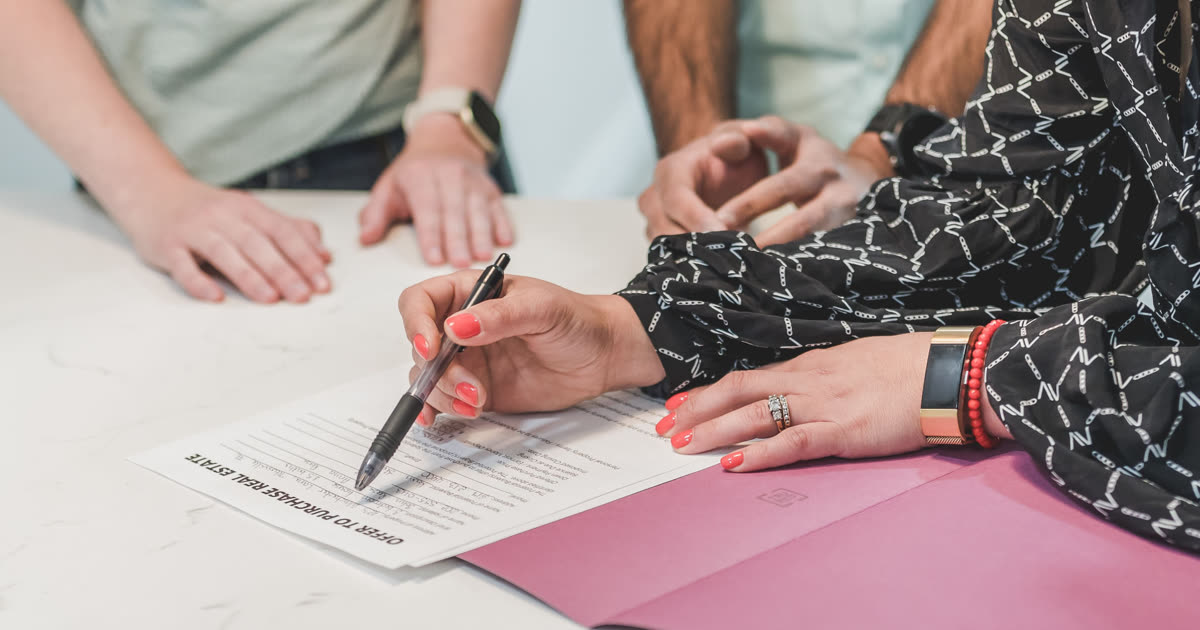 Two people reviewing and signing a finance agreement at a table